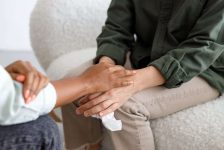 mental support to hold hands, handshake. An African-American female psychologist holds an appointment with a patient in the office mental support to hold hands, handshake. An African-American female psychologist holds an appointment with a patient in the office. mental health and moral support. a female patient with mental difficulties and a mental disorder. depression and insomnia